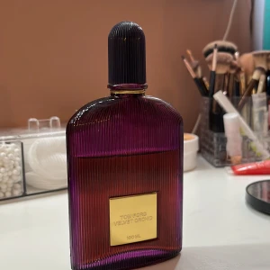 Tom Ford Velvet Orchid parfym 100ml - Lyxig parfym från Tom Ford i modellen Velvet Orchid. Flaskan är djupt lila med räfflad yta och har en elegant guldig etikett framtill. Rymmer 100 ml och har en exklusiv och modern design som sticker ut på sminkbordet. Är mindre än hälften använt.