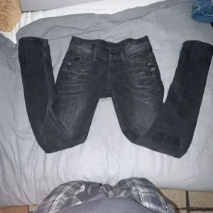 G star jeans - Säljer ett par svarta skinny jeans från G-Star i modellen Raw Denim. Jeansen har klassisk femficksdesign, smal passform och snygga slitningar för en cool look. Perfekta för dig som gillar en tajt stil och streetkänsla.