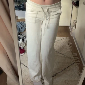 Vita mjukisbyxor med snörning  - Säljer ett par vita mjukisbyxor i storlek XS. Byxorna har resår i midjan med snörning, raka ben och fickor både fram och bak. Perfekta för chill dagar eller när du vill vara extra bekväm. Mjukt material som känns skönt mot huden.