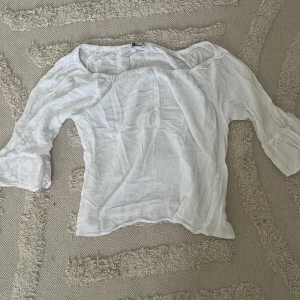 Vit offshoulder blus från Cubus - Säljer en vit blus i luftig bomull med offshoulder-modell och trekvartsärmar med volangdetalj. Blusen har en lätt rynkad struktur och är superenkel att matcha med jeans eller kjol.