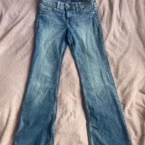 Blå flared jeans från H&M - Blåa flared jeanes från H&M. Benen lite trasiga.