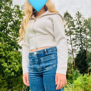 Vit croppad hoodie med dragkedja - Säljer en stilren vit croppad hoodie med dragkedja. Tröjan har lång ärm och en tightare passform som sitter snyggt på kroppen. Perfekt att matcha med jeans eller kjol för en trendig look.