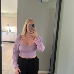 Ljuslila croppad blus med puffärm - Säljer en ljuslila croppad blus med smockad midja och långa puffärmar. Toppen har en fyrkantig urringning. Från h&m, storlek s. 