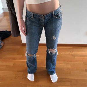 Lågmidjade jeans med hål - Så fina jeans med hål/slitningar i, de är låga, utsvängda och har detalj på bakfickorna, tyvärr passar de inte som syns på bilderna och det är just därför jag valde att sälja dem🩷 Skriv om du vill ha mer info eller bilder! Midjemått: 44 cm🩷