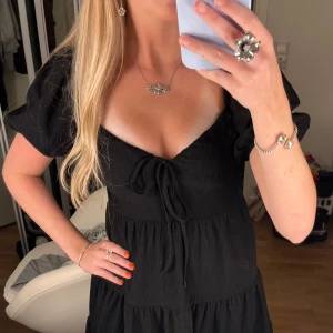 Svart kort klänning med puffärm - Supersöt svart klänning med puffiga korta ärmar och v-ringad urringning med snörning framtill. Helt ny, passar dig som är mellan 158-170 cm lång❣️