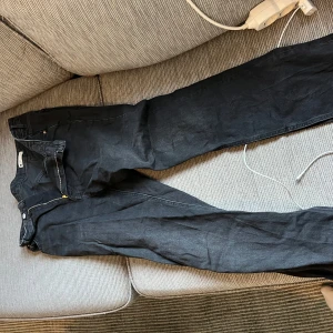 Svarta jeansbyxor med rak passform - Säljer ett par svarta jeansbyxor med klassisk rak passform. Byxorna har dragkedja och knapp framtill samt fem fickor. Perfekta för dig som gillar en enkel och stilren look. Gina 
