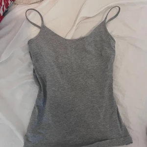 Grå tajt linnetopp  - Superskön grå linnetopp från 157 i storlek XS. Tunn och mjuk bomullsblandning med smala axelband och enkel, slim passform. Perfekt att styla med jeans eller shorts för en chill look. Materialet är 90% bomull, 5% viskos och 5% elastan. Helt ny aldrig använt!!