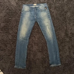 Replay Grover ljusblå jeans, stl 29/32 - Säljer ett par Replay Grover jeans i ljusblå tvätt med snyggt slitna detaljer. Klassisk femficksmodell med raka ben och slim passform. Jeansen har tydliga Replay-detaljer och är tillverkade i mjukt denimtyg. Perfekta för dig som gillar en avslappnad stil. För mer bilder och mått kom privat.