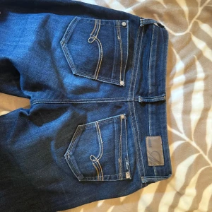 Mörkblå bootcut low waist  - Snygga mörkblå jeans från Mavi med klassisk bootcut-modell.  Lågmidjade i midjan och väldigt sköna. Modell Bella. Storlek 25/32