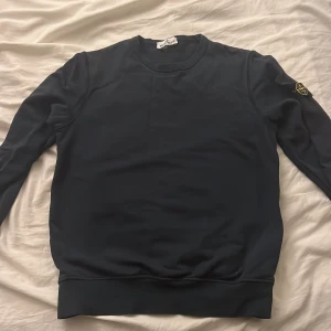 Mörkblå Stone Island Junior sweatshirt - Mörkblå sweatshirt från Stone Island. Bra skick. Tröjan är storlek 12a vilket borde passa om man är runt 155/162. Köpte den ifrån hemsidan. Priset är inte hugget i sten så kom bara med förslag😊