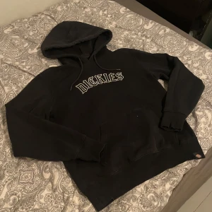Svart Dickies hoodie med broderad logga - Svart hoodie från Dickies i storlek XS med stor broderad logga i vitt på bröstet. Klassisk huva med snörning och magficka framtill. 