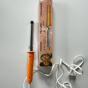 Jura Inter Electro locktång orange - Retro locktång med orange handtag och silverfärgad metallstav. Kommer i originalförpackning med instruktioner på sidan. Perfekt för dig som gillar vintageprylar och vill fixa snygga lockar hemma. Utrustad med vit sladd och klassisk design. Original från 70 talet den fungerar. 