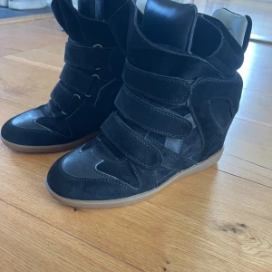 Svarta sneakers med kardborreband - Snygga svarta sneakers i mocka med flera kardborreband för en cool look. Skorna har en rund tå och en bekväm sula i gummi. Perfekta för en stilren och avslappnad stil.
