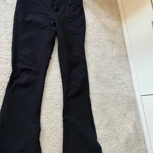 Svarta bootcut byxor från Gina Tricot - Snygga svarta bootcut byxor från Gina Tricot. Byxorna har en klassisk design med knappar i midjan och en stilren look. Perfekta för en trendig och bekväm stil.