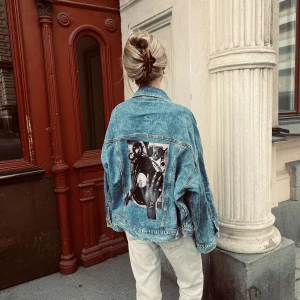 RHYTHM 001 - Jeansjacka från JAQUÍ med trycket RHYTHM 001 Ärmlängd (från armhåla): 46 cm Byst: 72 cm Längd: 62 cm Storlek: M Modellen är 170 cm lång.