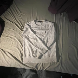 Vit långärmad tröja från Polo Ralph Lauren - Säljer en stilren vit långärmad tröja från Polo Ralph Lauren. Tröjan har en klassisk design med en liten broderad logotyp på bröstet. Perfekt för en avslappnad och snygg look. 🕶️Litet hål vid loggan därav de lägre priset. Priset e nt hugget i sten heller