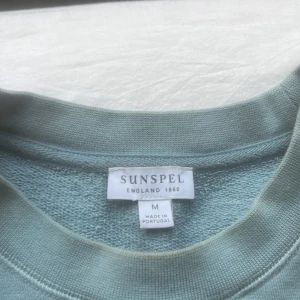 Ljusblå tröja från Sunspel - Säljer en stilren ljusblå tröja från Sunspel. Tröjan har en klassisk rund hals och långa ärmar, perfekt för en avslappnad look. Tillverkad med högkvalitativt material för en bekväm känsla. Perfekt för kyligare dagar i vår och sommar. Nypris var 2300 kr, mitt pris 999 kr. Pris kan diskuteras vid snabb affär.