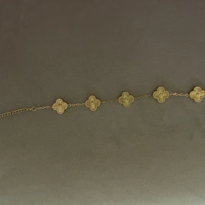 Guldarmband med fyrklöverdesign - Elegant guldarmband med flera fyrklöverformade hängen. Perfekt för att lägga till en touch av lyx till din outfit. Hängena är jämnt fördelade längs kedjan och ger en stilren look.