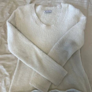 Vit fluffig tröja från Wera - Mysig och stilren vit tröja från Wera. Den har en fluffig textur som ger en extra dimension till din outfit. Perfekt för kyliga dagar med sin långärmade design. Enkelt att matcha med olika stilar och tillfällen.