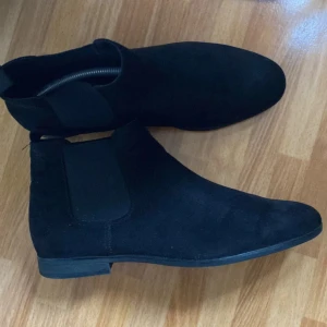 chelsea boots - Snygga svarta chelsea boots i mocka med rund tå och elastiska paneler på sidorna för enkel på- och avtagning. Perfekta för en stilren look. Skriv till mig vid minsta lilla fundering! MVH