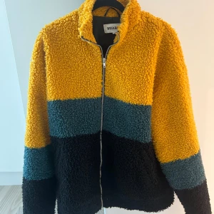 Flerfärgad teddyjacka från Weekday - Säljer en teddyjacka från Weekday i färgerna gul, blå och svart. Använd men i väldigt gott skick. Väldigt varm. I storlek M men sitter mer som L/XL. Nypris 1300kr.