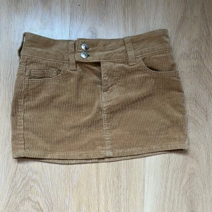 Beige kort kjol - Säljer denna beiga, korta kjolen från HM. Den är gjord i manchestertyg och sitter som en pennkjol. Säljer då den har blivit för liten och kan därför inte visa bilder med den på. En liten svart fläck på ena bakfickan men annars inga defekter. Storlek 32 💕