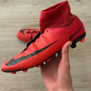 Röda Nike Mercurial fotbollsskor - Säljer ett par röda Nike Mercurial fotbollsskor utan snörning men som så klart går att sätta på själv. Skorna är i bra skick men höger är lite mer sliten! Skorna är AG. Dessa skor är sällsynta och tillverkas inte längre