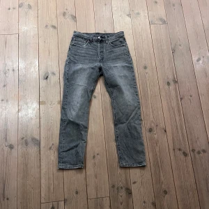 Grå jeans från Levi's - Snygga grå jeans från Levi's med klassisk femficksdesign och knappgylf. De har en rak passform och är tillverkade i slitstarkt denim. Perfekta för en avslappnad stil.
