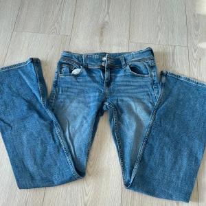 Blå jeansbyxor från Gina Tricot( lågmidigade) - Snygga blå jeansbyxor från Gina Tricot med låg midja och vida ben. Byxorna har dubbla knappar i midjan och klassiska femficksdetaljer. Perfekta för en avslappnad stil.🩷🩷