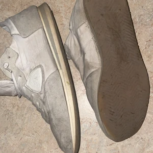 Philippe modell trpx  - Säljer ett par grå sneakers med snörning och rund tå. Skorna har en kombination av mocka och syntetmaterial, vilket ger dem en stilren look. Perfekta för vardagsbruk.