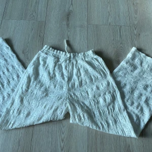 Vita byxor från Zara - Säljer ett par vita byxor från Zara med elastisk midja. Byxorna har ett hålmönster och är tillverkade i ett lätt och luftigt material, perfekt för varmare dagar🩷🩷.