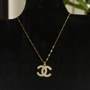 Guldhalsband med glittrig hängsmycke - Elegant guldhalsband med ett glittrigt hängsmycke. Kedjan är tunn och vriden, vilket ger en stilren look. Perfekt för att lägga till lite glamour till din outfit.