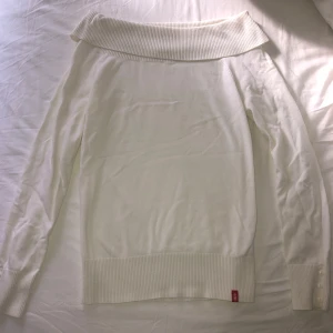 Vit offshouldertröja från edc - Säljer en vit offshouldertröja från edc med bred ribbad kant upptill och nedtill. Tröjan har långa ärmar och dekorativa knappar vid ärmsluten. 