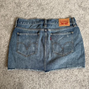 Lågmidjad mini jeanskjol Levis  - Säljer denna otroligt fina jeanskjol från Levis som endast är använd en gång då den är för liten. Storlek 26 står på kjolen men den är stor i storleken samt stretchig.  Midjemått 38 cm Längd 31 cm  Pris går att förhandla.