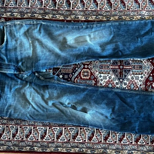 Blå raka jeans med slitningar - Coola blå jeans med en bred passform från ett ovanligt märke, det är dragkedja gylf och massa coola slitningar på jeansen. Det negativa är att det är skada vid skreven men dem är lagade så det knappt syns 