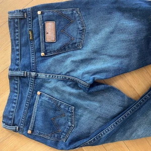 Lågmidjade bootcut vinted jeans  - Säljer ett par klassiska blå jeans från Wrangler, bootcut och snygga detaljer i guld. Min mammas gamla! Lite slitna längst ner, men annars inga tydliga skador. Jag är 162 typ och de är för långa för mig. 💖💖