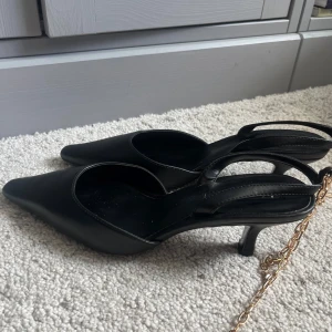 Spetsiga svarta slingback klackar  - Supersnygga spetsiga svarta slingback klackar från Mango! Aldrig använda därav i fint skick! De har ett smycke som ska sättas runt ankeln, men går enkelt att klippa/bita av om man ej vill ha kvar det!