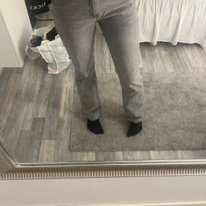 Grå raka jeans - Säljer ett par grå jeans med rak passform och klassisk femficksdesign. Jeansen har normal midja och stängs med dragkedja och knapp. Perfekta för en avslappnad och stilren look.