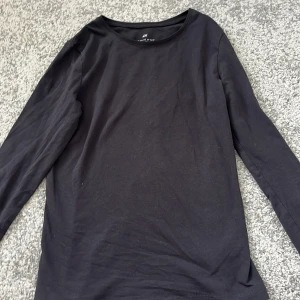 Svart långärmad tröja från H&M 100% bomull - En enkel svart långärmad tröja från H&M. Tröjan har rund halsringning och är tillverkad i ett mjukt 100% bomullsmaterial. Perfekt basplagg att ha i garderoben.
