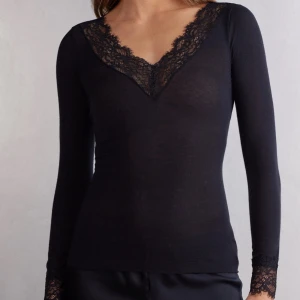 Svart långärmad topp med spets - Svart långärmad topp med djup v-ringning och fina spetsdetaljer längs halsringningen. Tunn och mjuk, perfekt att styla till olika outfits. Snygg och enkel design. kan tänka mig att gå ner i pris så det är bara o höra av sig 