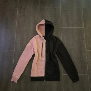 Rosa och svart hoodie - Säljer en hoodie i färgerna rosa och svart. Tröjan har dragkedja framtill och huva med snören. Perfekt för en avslappnad stil och enkel att matcha med jeans eller leggings.😽❤️❤️