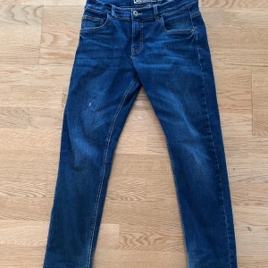 Jeans - Säljer ett par snygga blåa jeans. Dom är i bra skick fast det finns en väldigt liten skada (se bild)