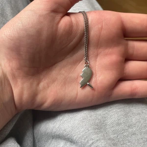 Silverfärgat halsband  - MARIA NILSDOTTER LIKNANDE HALSBAND Säljer ett stilrent halsband i silverfärg med en unik berlock. Kedjan är tunn och smidig, perfekt för dig som gillar enkla men personliga smycken. Passar till många olika stilar och tillfällen.