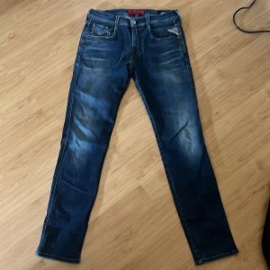 Blå Replay Anbass jeans - Säljer ett par blå Replay Anbass jeans med snygga slitningar och tvättade detaljer. 