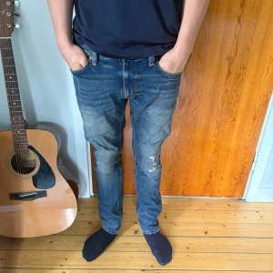 Blå jeans från Nudie Jeans - Säljer ett par klassiska blå jeans från Nudie Jeans med snygg slitning. Storlek 29/30 och modell lean dean