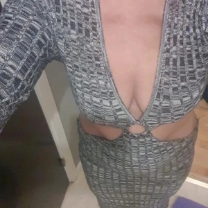 Grå långklänning från NA-KD med cutouts - Säljer en snygg långklänning från NA-KD i grått och svart mönster. Klänningen har djup v-ringning, cutouts vid midjan och en ringdetalj framtill. Långärmad och figurnära passform, perfekt för dig som vill sticka ut.