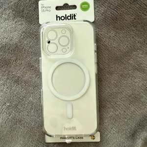 Holdit MagSafe skal iPhone 16 Pro - Snyggt och stilrent MagSafe-skal från Holdit till iPhone 16 Pro. Skalets design är transparent med en vit cirkel för MagSafe-funktion så kan du använda trådlös laddning. Nypris 300 kr. Helt ny med plast på. Tillverkat i slitstark plast som skyddar mobilen utan att dölja dess utseende. 