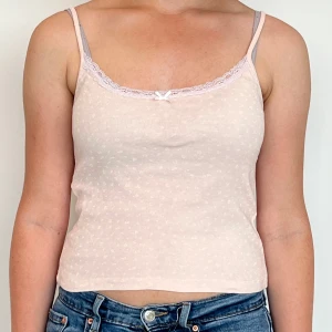 Rosa linnetopp från Brandy Melville  - Jättefin och söt linnetopp från Brandy Melville💕💕 Den har vit spets och små vita blommor på. Passar att ha på den på vardagen eller pyjamas! Storleken är ONE SIZE.