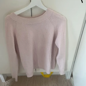 Ljusrosa stickad tröja - Supermysig ljusrosa stickad tröja med bred ribbad kant vid halsen och långa ärmar. Perfekt att slänga på sig när det är kyligt ute. Enkel och stilren design som passar till det mesta.