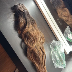 Brun balayage löshår clip-on - Säljer ett set med vågigt löshår i clip-on-modell. Färgen är en snygg balayage med mörkbrun botten som övergår i karamellbruna längder. Perfekt för dig som vill ha extra volym och längd. Håret är syntetiskt och har naturlig glans.